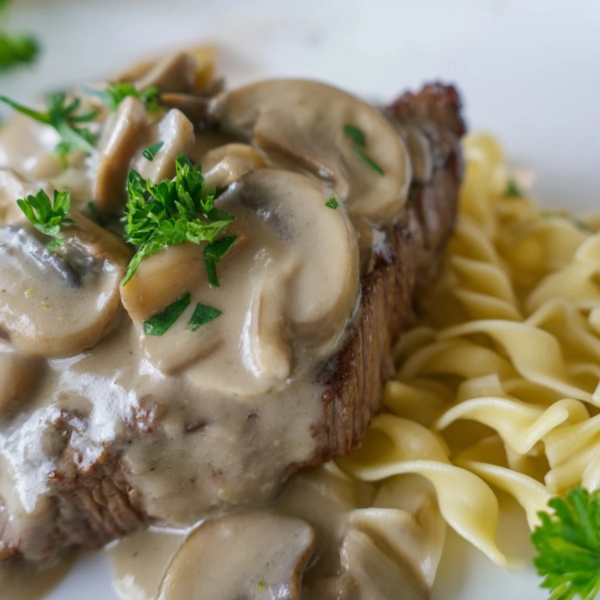 Creamy Beef Stroganoff with Mushroom Gravy over tender egg noodles, garnished with fresh parsley, ready to serve.