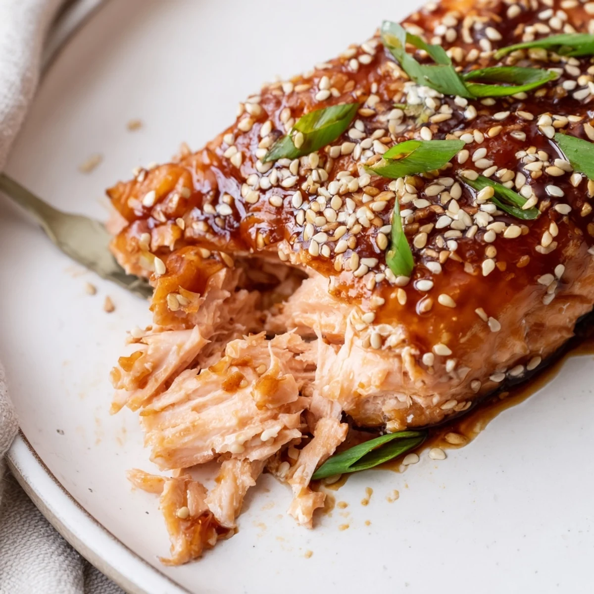 Flaky, tender Baked Salmon with Teriyaki Glaze and Sesame is served over white rice with lime wedges.