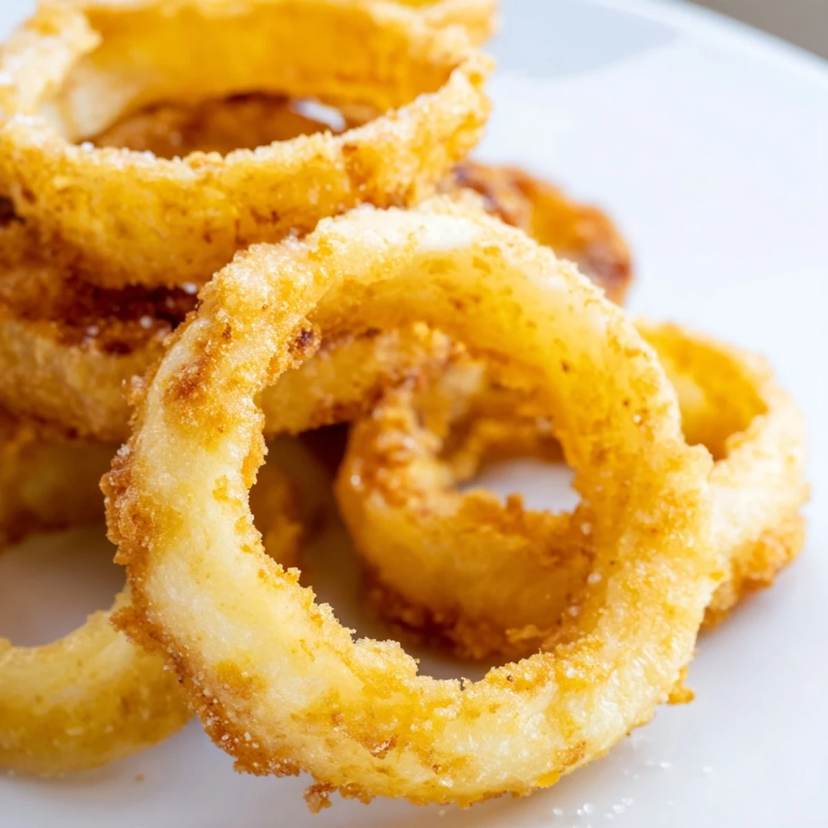 Crispy Onion Rings with Batter served hot alongside a burger, perfect for an appetizer or game-day snack.