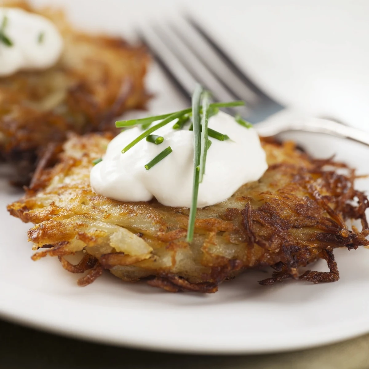 Crispy Potato Latkes are served hot with creamy sour cream for a classic bite.
