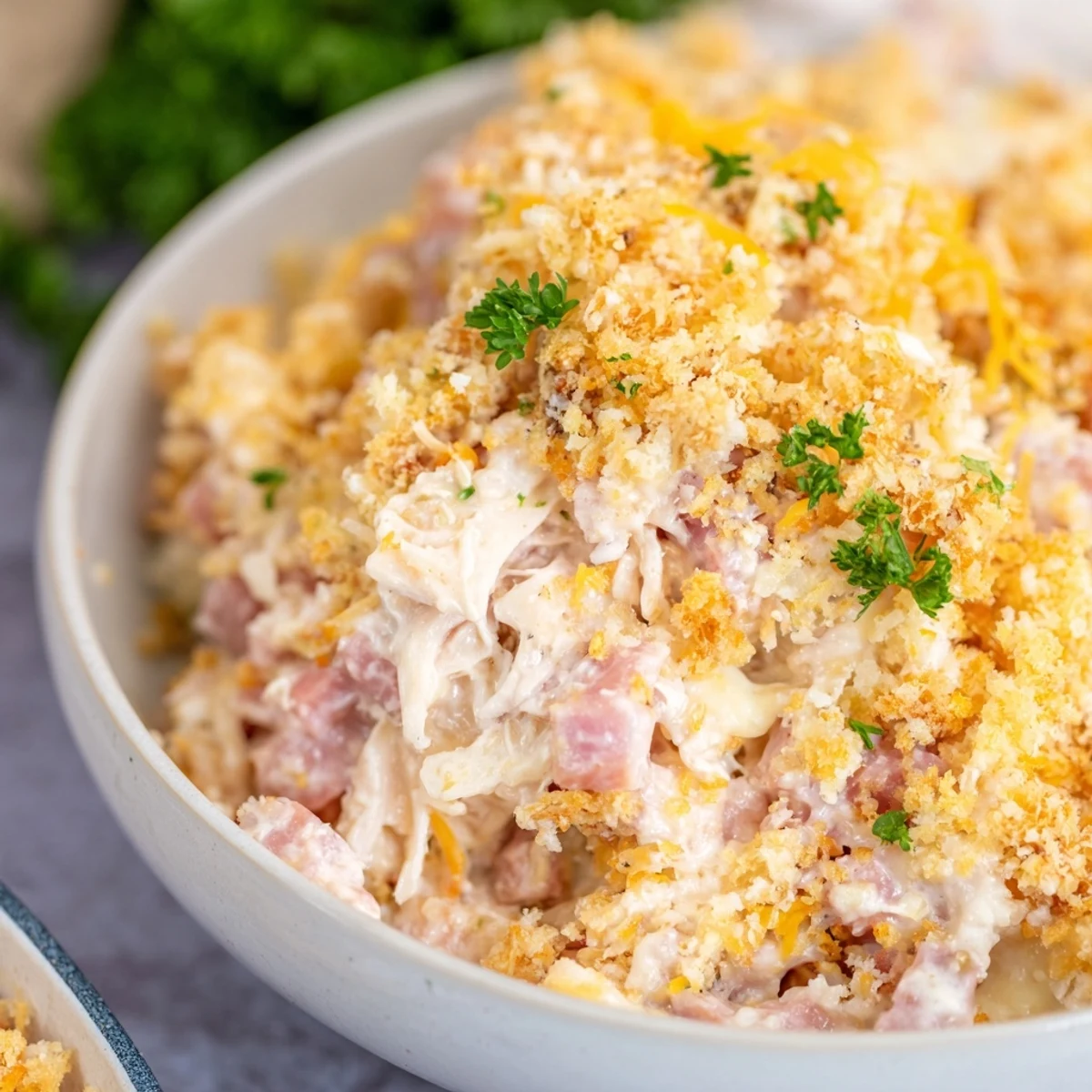 Spoon serving of creamy Chicken Cordon Bleu Casserole with ham and Swiss on a plate with salad.