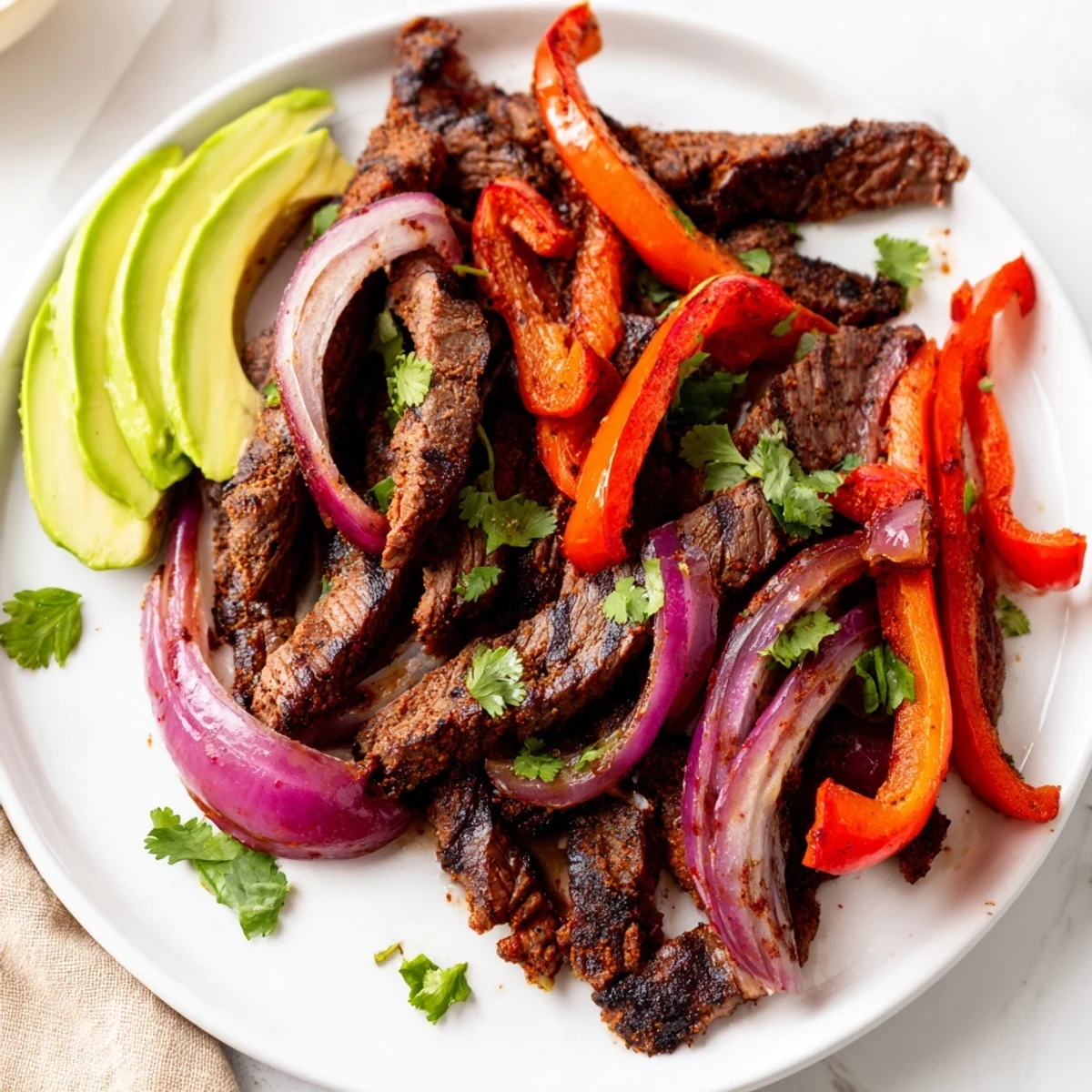 Platter of Sheet Pan Steak Fajitas with Bell Peppers and Onions topped with fresh cilantro and lime wedges.