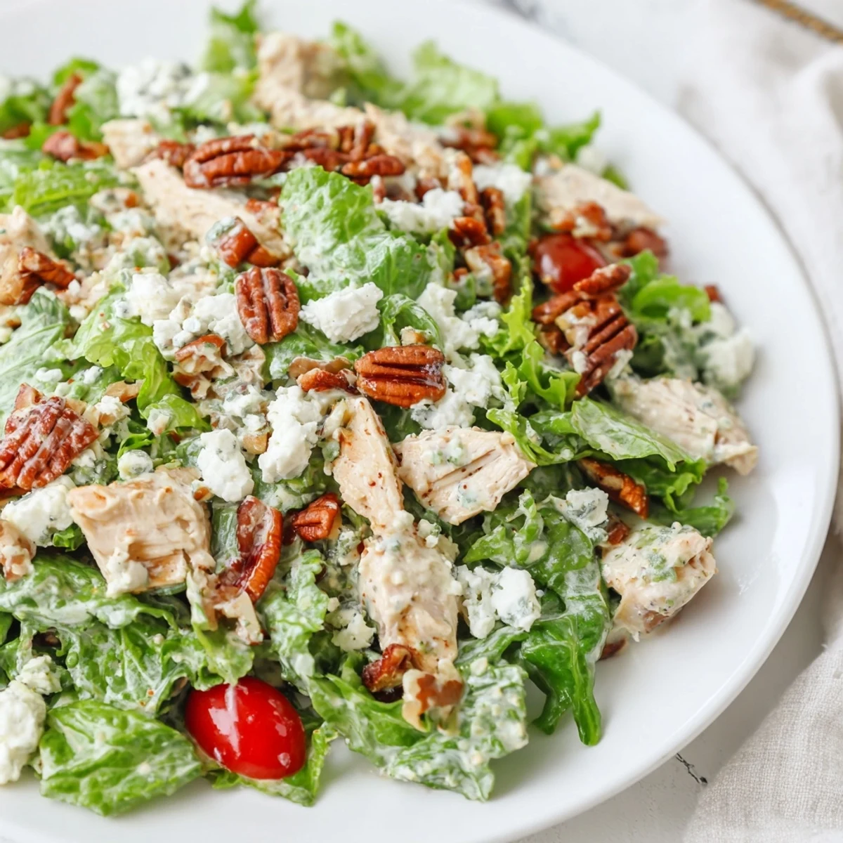Golden-brown toasted pecans add crunch to a vibrant Chicken Pecan Salad with Dressing, served on fresh greens.