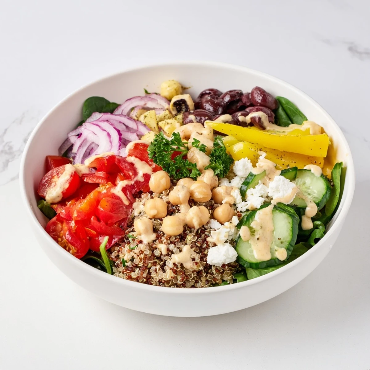 Fresh Mediterranean Dinner Grain Bowl piled with spinach, tomatoes, cucumber, and feta, garnished with parsley and dressed in creamy tahini.