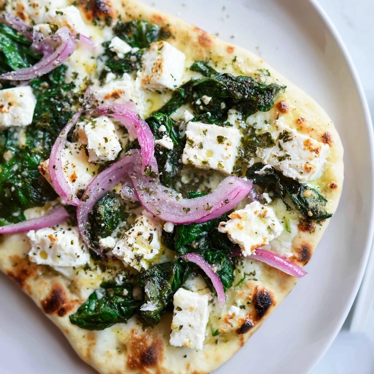 Spinach and Feta Flatbread Pizza features a crispy crust and fresh garlic aroma, served warm with a slice lifted.  