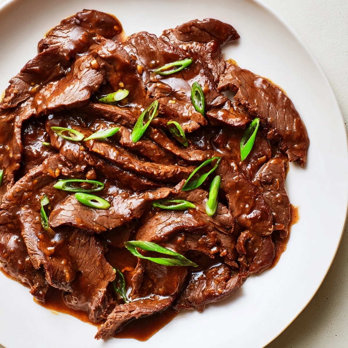 Tender, thin slices of Ultimate Slow Cooker Mongolian Beef simmered in glossy sauce over fluffy steamed rice, ready to serve.