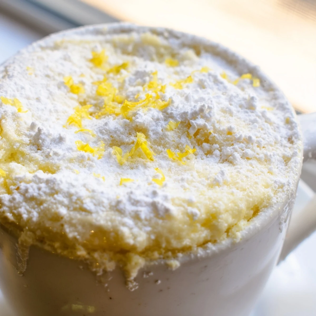 For a delightful treat, the Lemon Cottage Cheese Mug Cake pairs perfectly with a dollop of yogurt and fresh berries beside the mug.