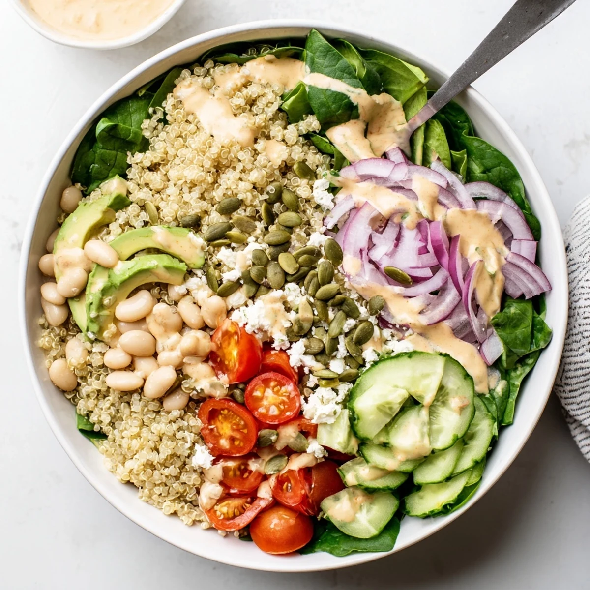 Colorful Spinach & White Bean Ultimate Protein Power Bowl with quinoa, tomatoes, and tangy lemon tahini dressing.