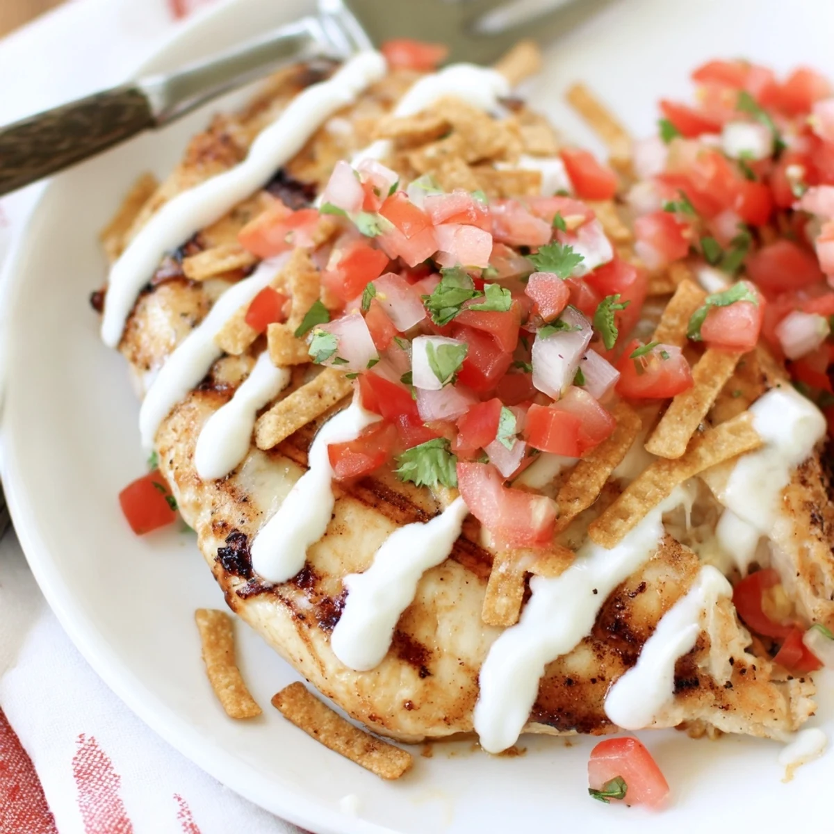Golden-brown grilled Fiesta Lime Chicken breasts topped with melted Mexican cheese blend, drizzled with creamy Mexi-ranch sauce, and garnished with fresh pico de gallo and crunchy tortilla strips.
