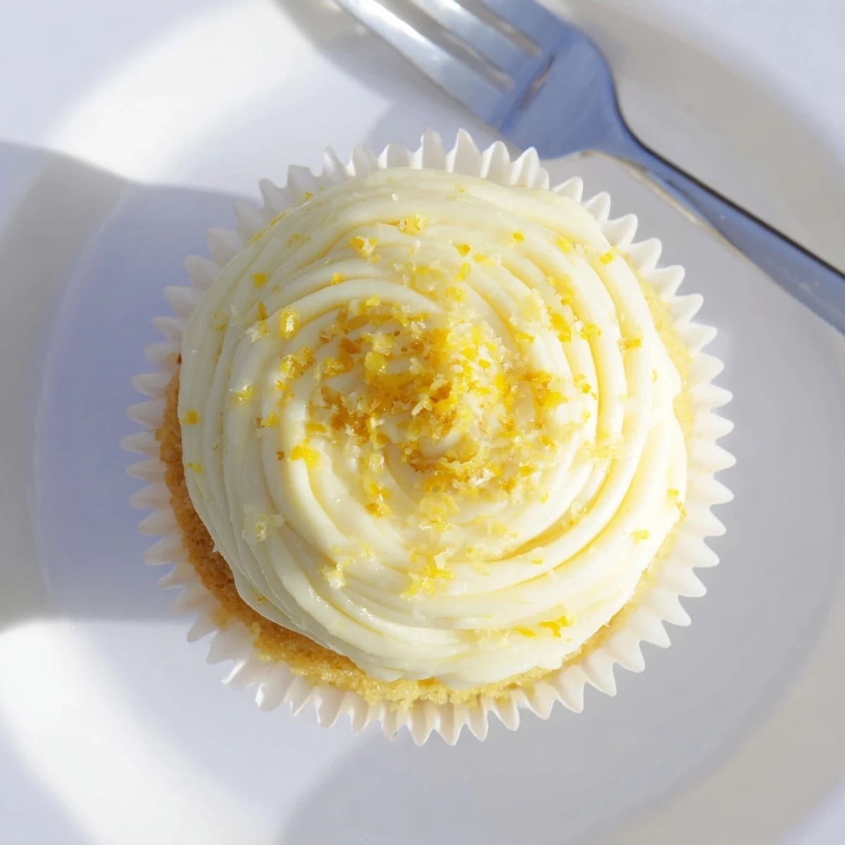 A stack of three Limoncello Cupcakes with fluffy lemon buttercream frosting and fresh zest garnish.