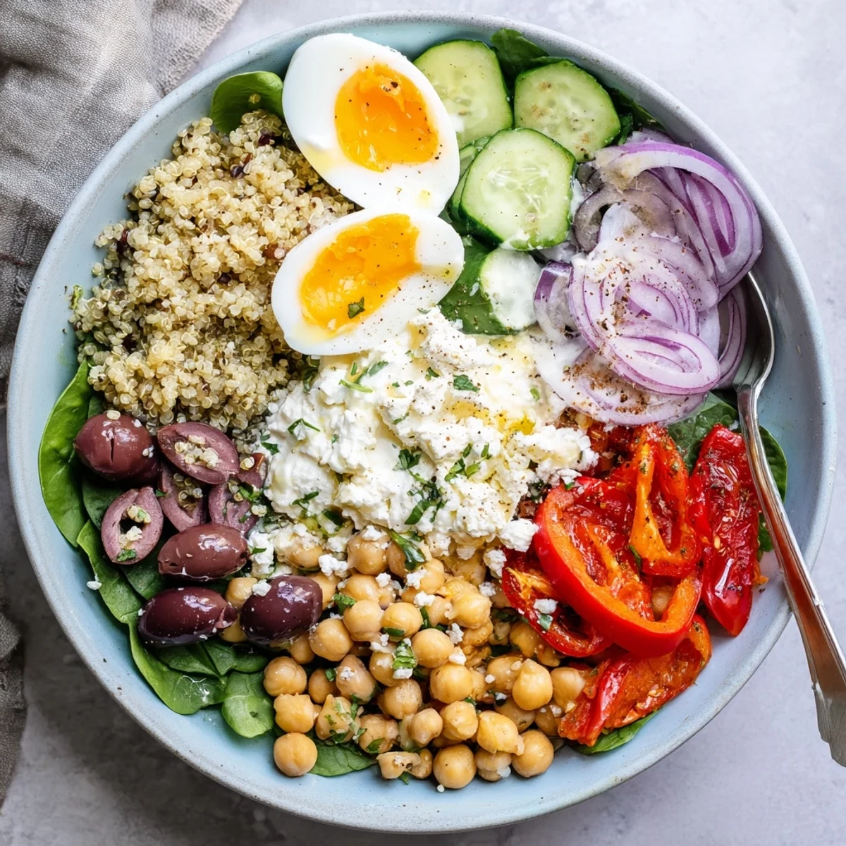 A close-up of High Protein Mediterranean Breakfast Bowls with jammy eggs, creamy Greek yogurt, and vibrant veggies on fluffy quinoa.