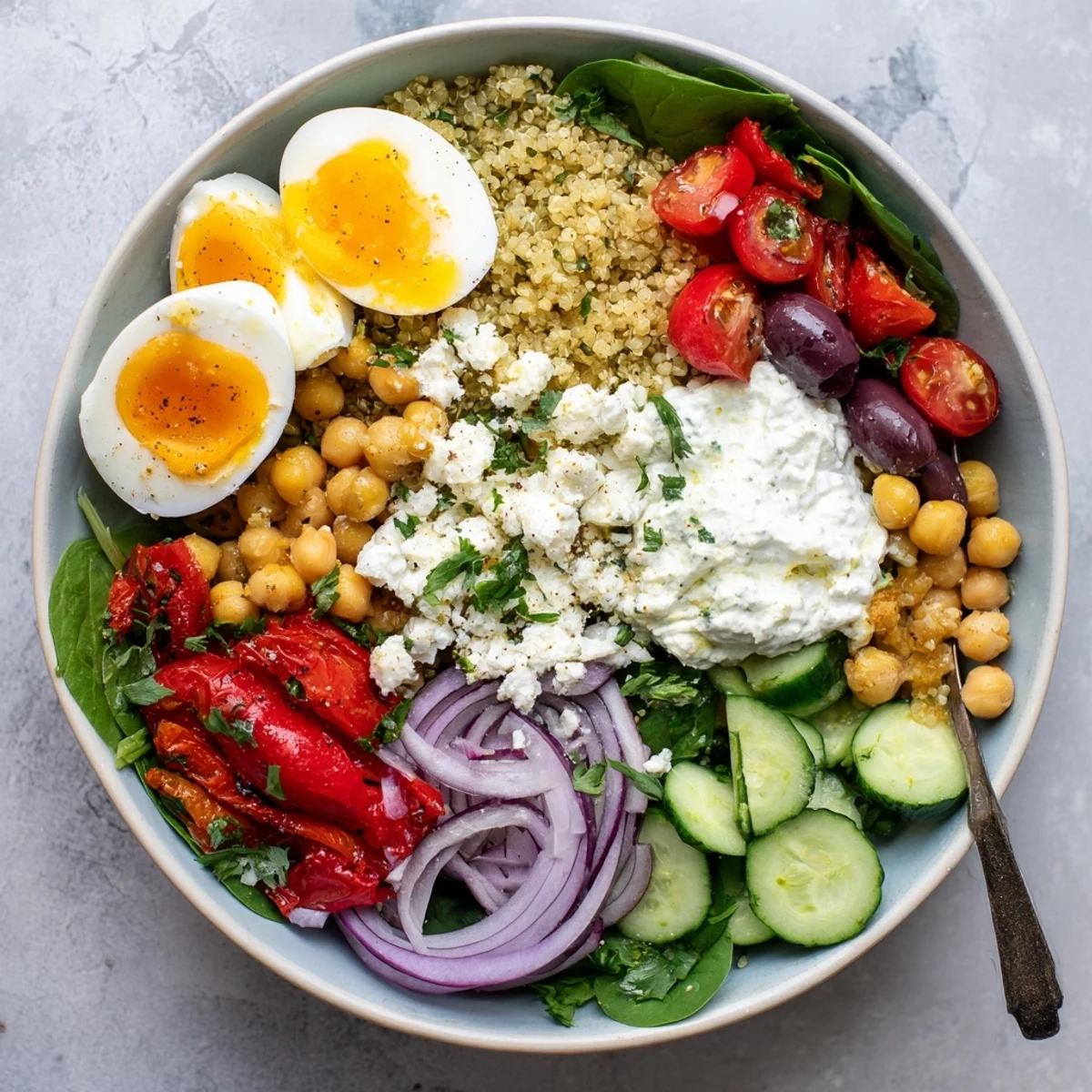 High Protein Mediterranean Breakfast Bowls topped with chickpeas, feta, and kalamata olives, drizzled with olive oil on a rustic table.