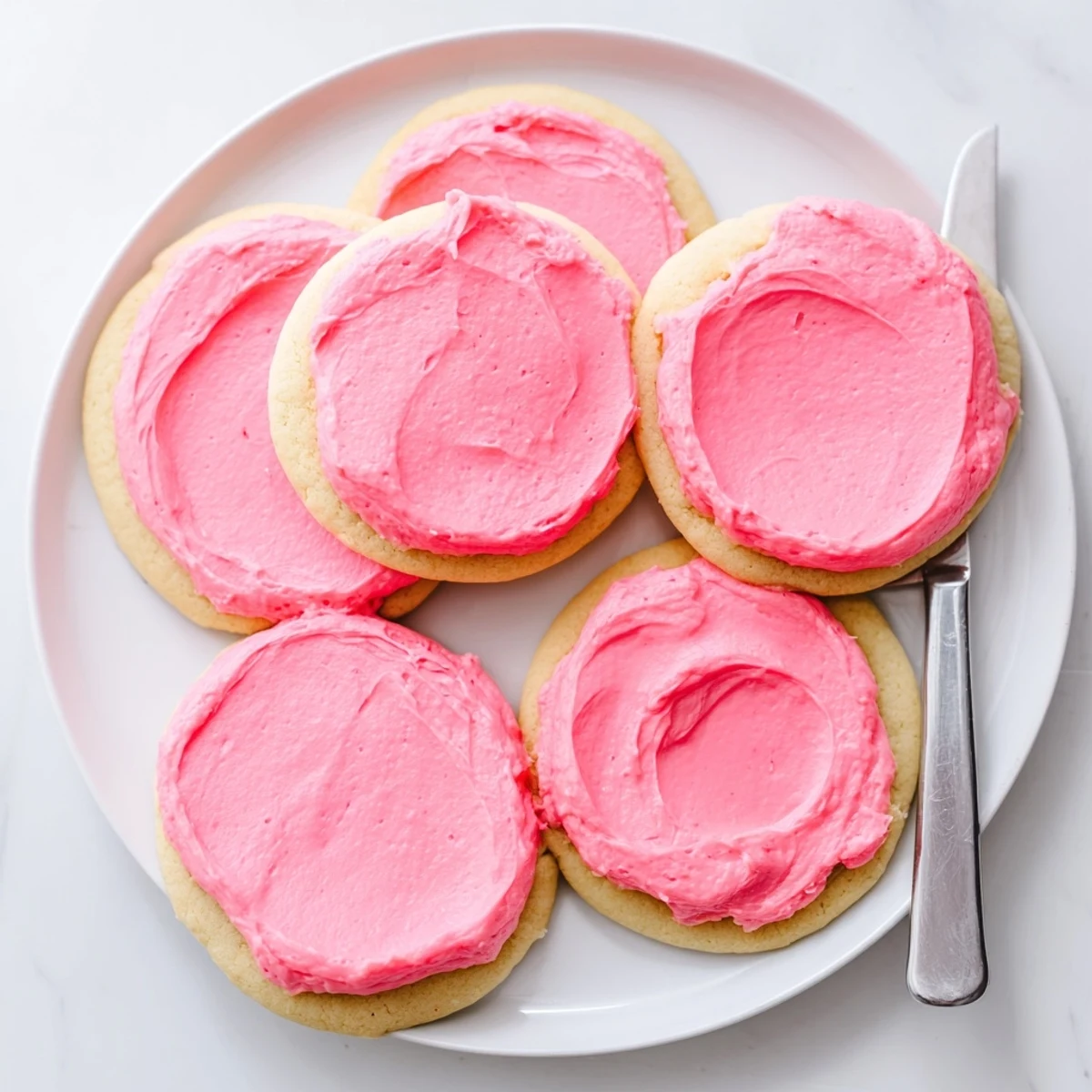 Hand holding a Crumbl Pink Sugar Cookie against a rustic table setting, perfect for a dessert platter.
