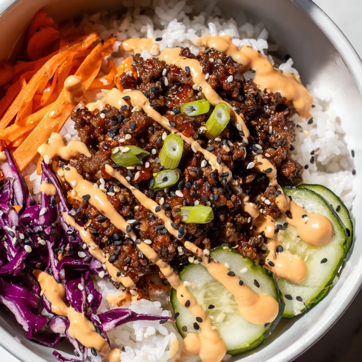 Bright Korean Beef Bowl with Spicy Mayo over white rice, topped with red cabbage and green onions.