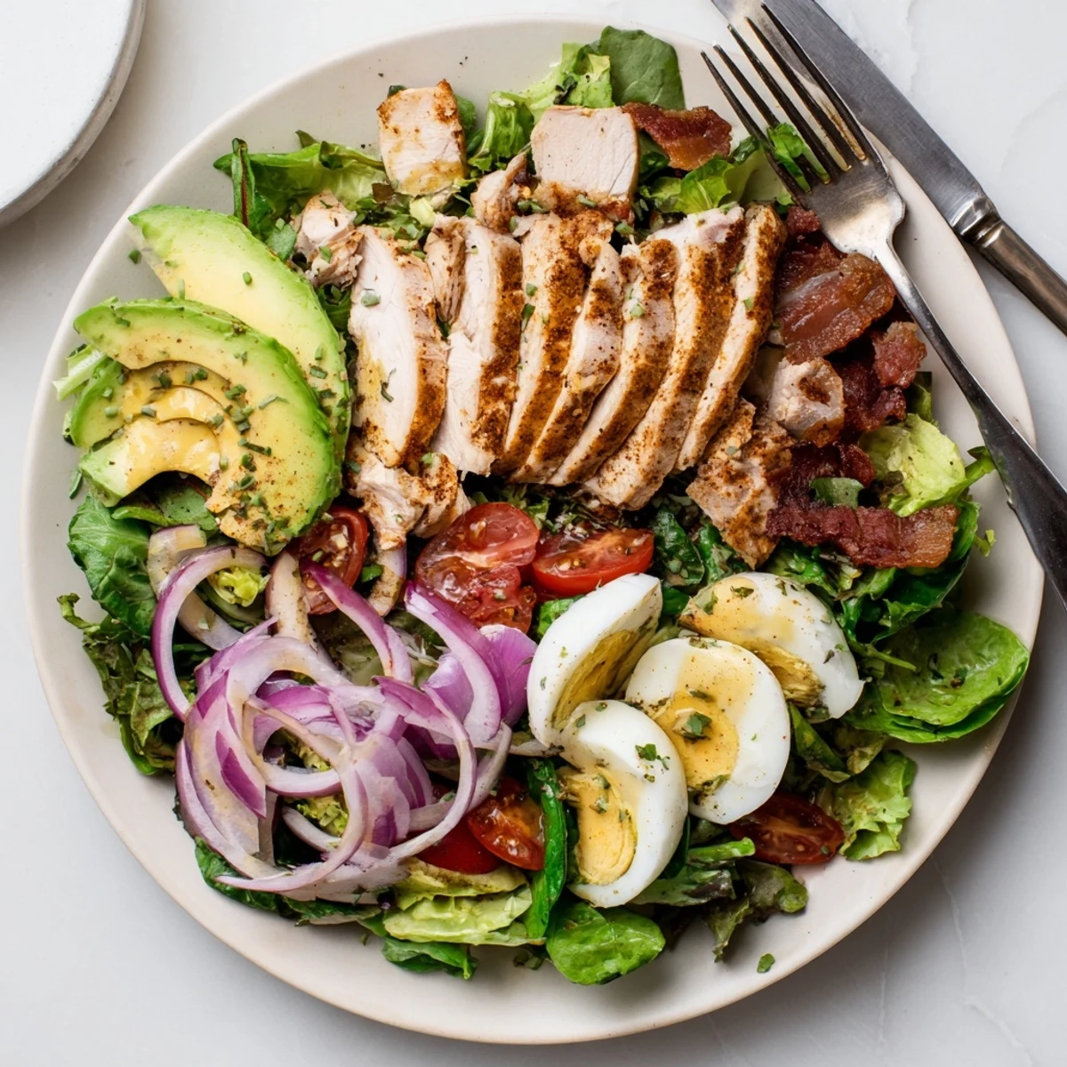 A vibrant Paleo Grilled Chicken Cobb Salad with honey Dijon dressing, featuring sliced grilled chicken, crispy bacon, creamy avocado, and hard-boiled eggs on fresh greens.