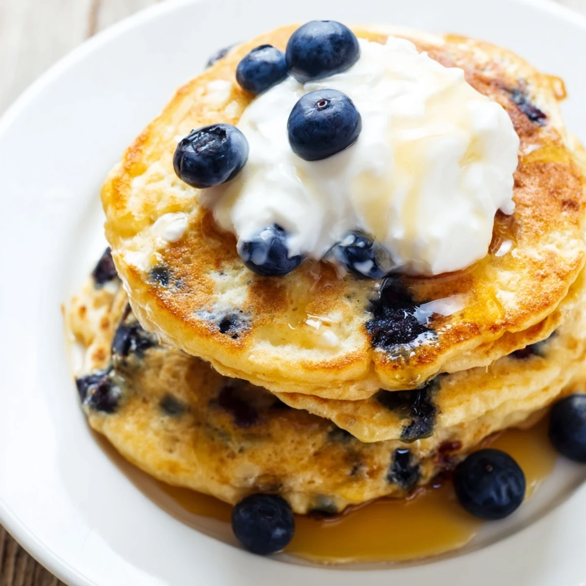 Warm Greek Yogurt Blueberry Pancakes served on a plate, garnished with extra blueberries and a dollop of tangy yogurt.