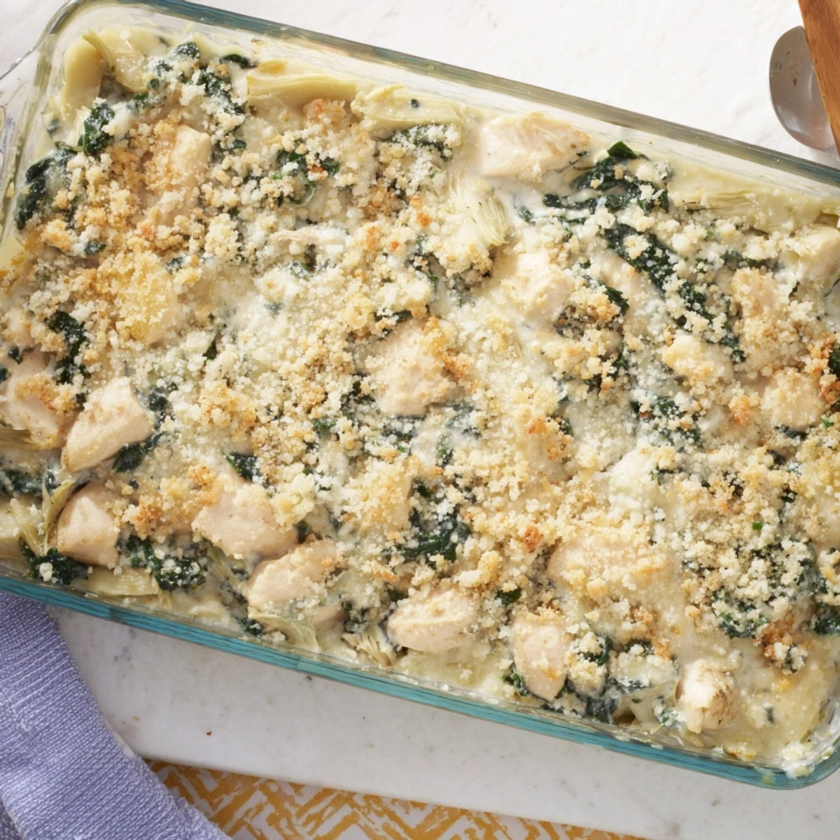 Golden brown high protein spinach and artichoke chicken casserole with bubbly cheese topping