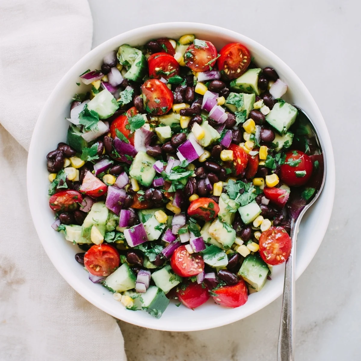 Colorful chopped black bean salad bowl with fresh vegetables and creamy avocado cubes