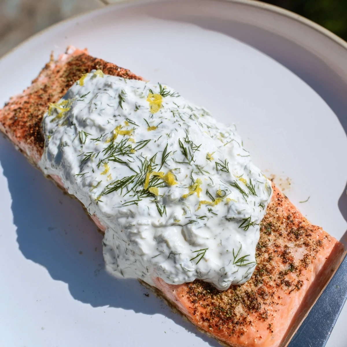 Healthy Mediterranean salmon dinner plated with tangy lemon dill yogurt and garnished with fresh herb sprigs