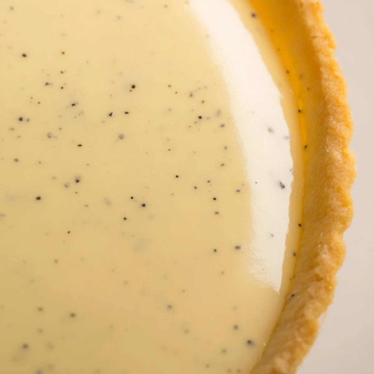 Golden vanilla bean pastry cream tart with crisp buttery crust and glossy finish