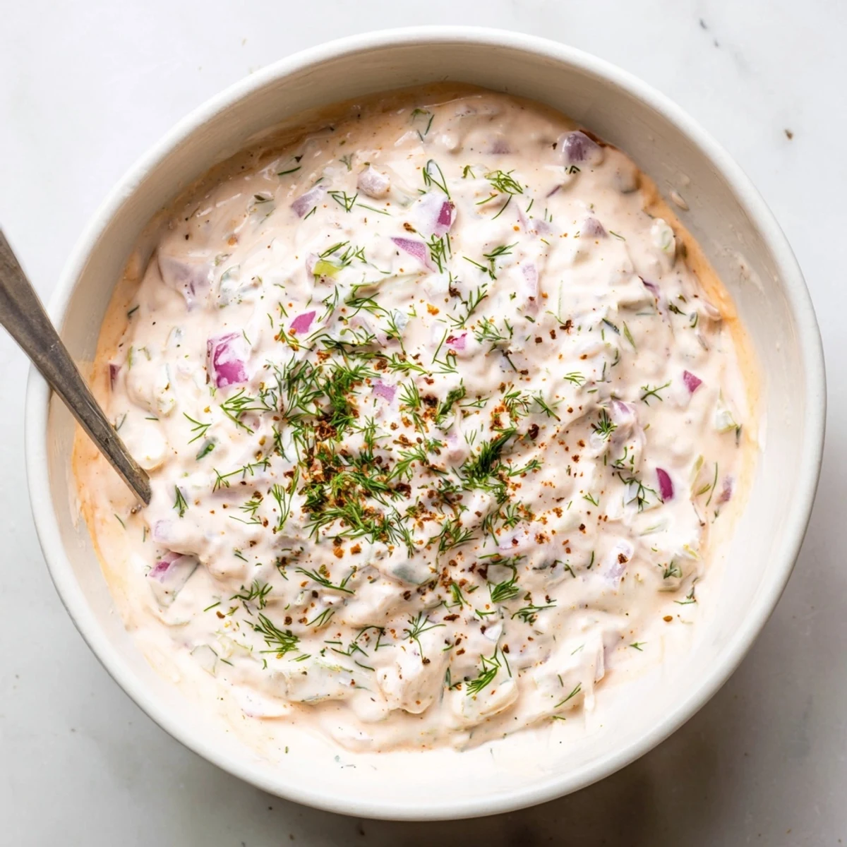 Thick spicy dill pickle burger sauce dolloped on a plate with chopped pickle bits visible