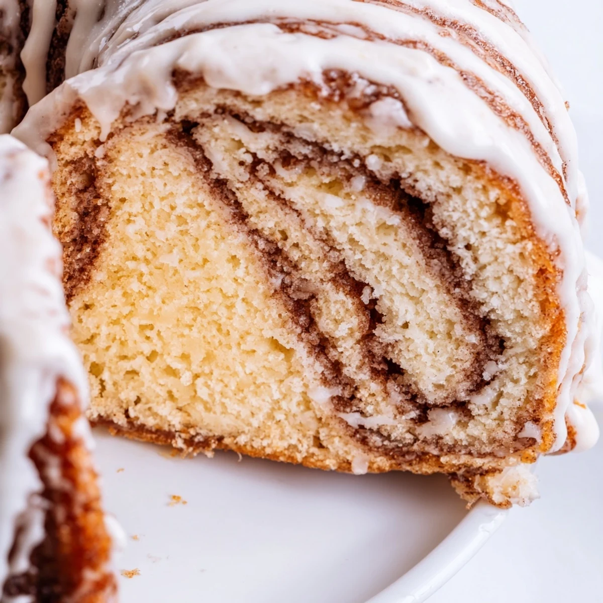 Golden cinnamon roll cake with buttery swirls and vanilla glaze drizzled over top