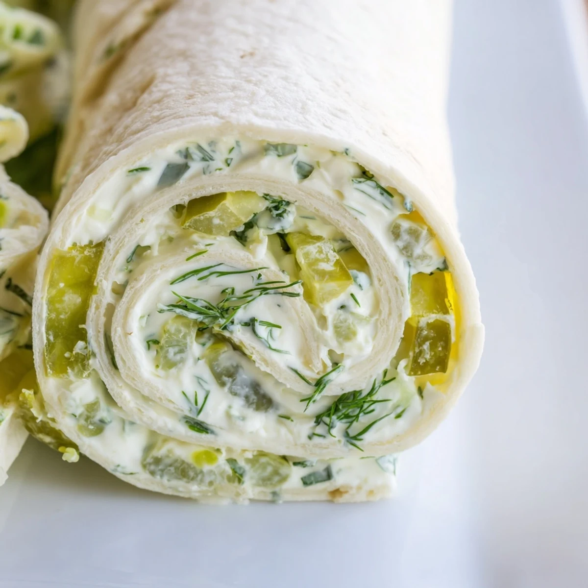 Green-stuffed tortilla pinwheels loaded with chopped dill pickles and herbed cheese on serving platter