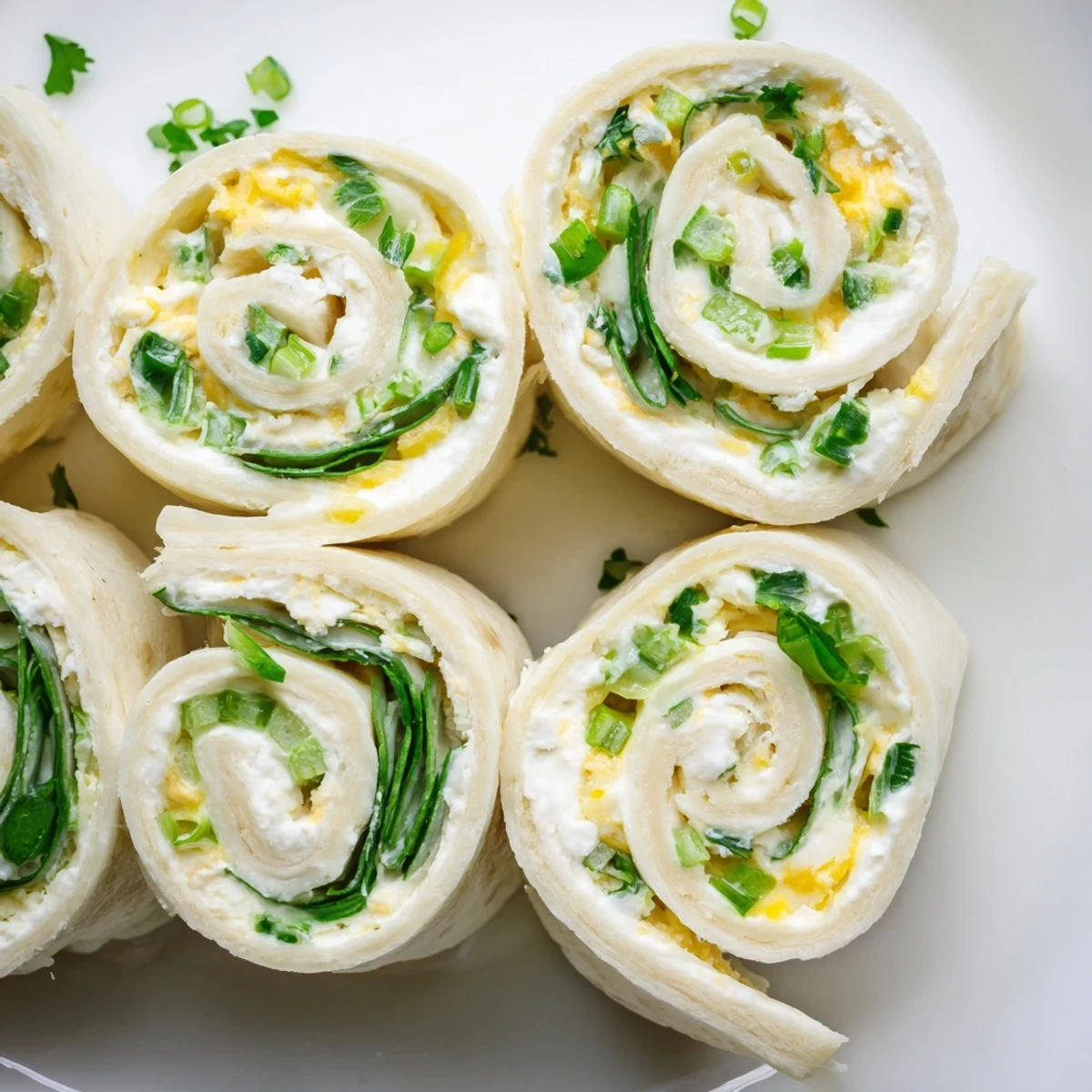 Savory cream cheese pinwheels sliced into rounds revealing colorful vegetable flecks throughout the white filling