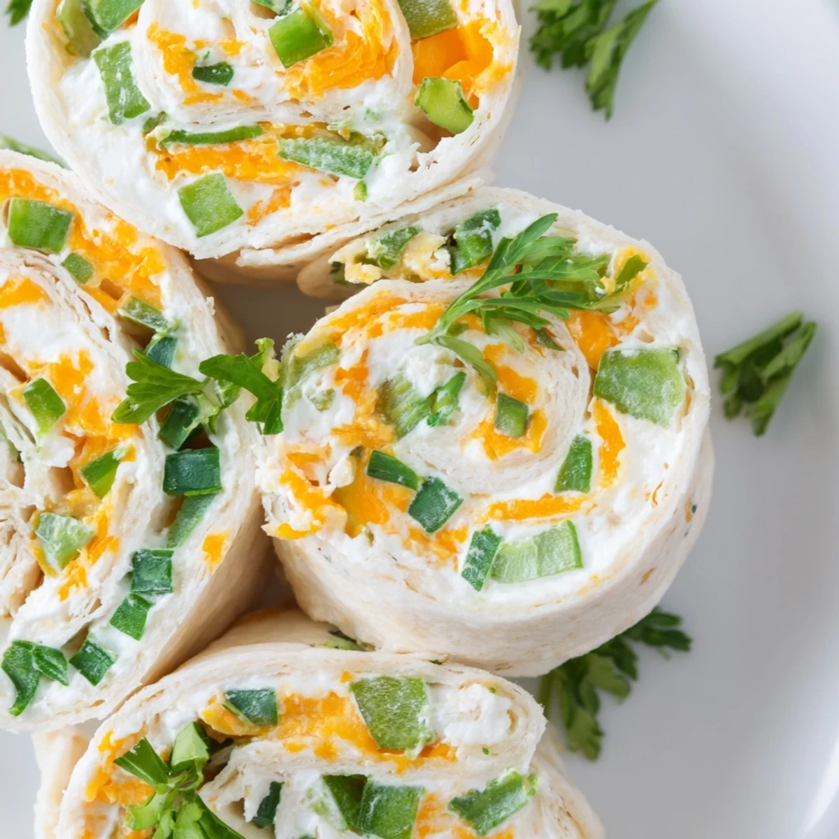 Rolled tortilla pinwheels filled with creamy cheese mixture, topped with fresh parsley and ready for party serving
