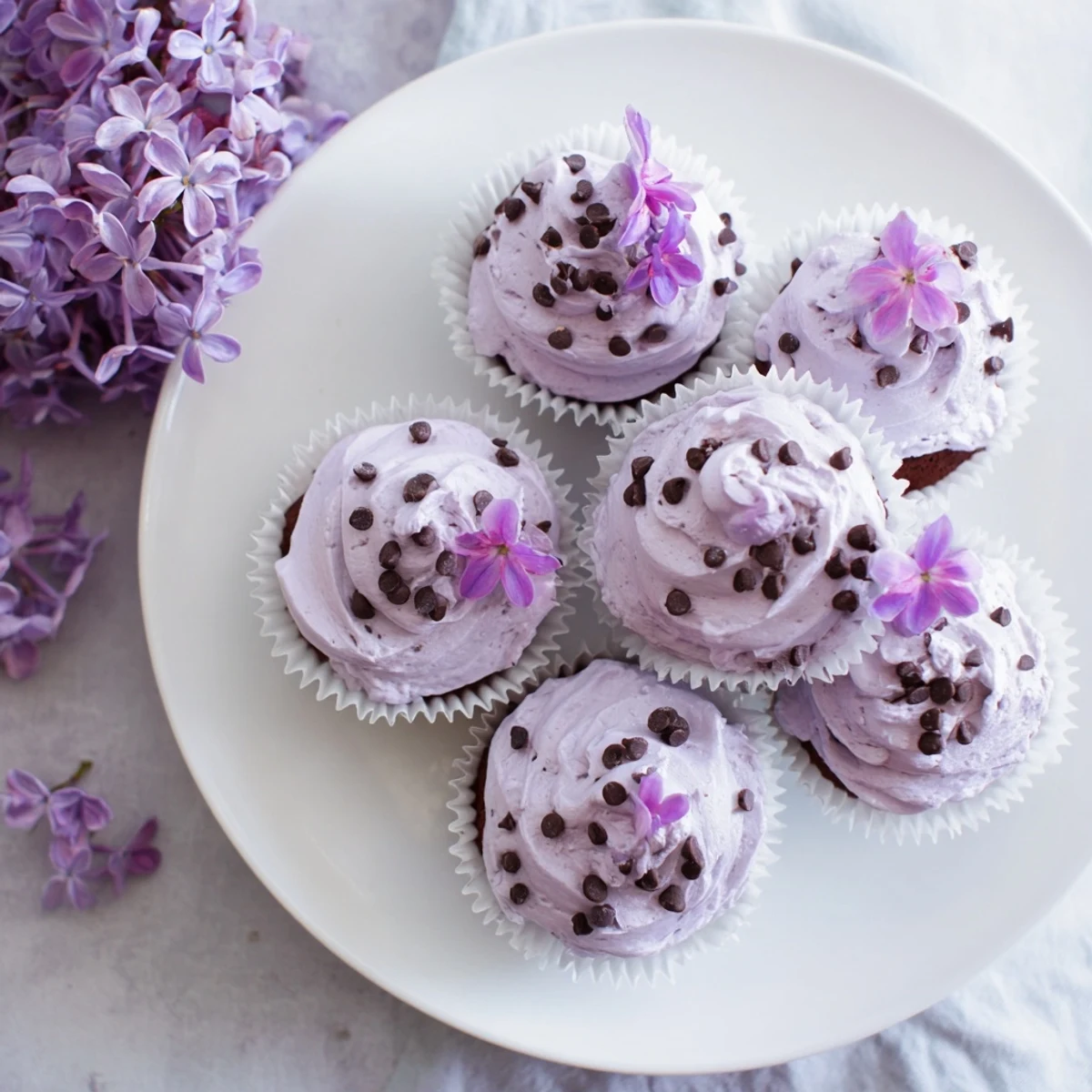 Small batch lilac chocolate cupcakes topped with fluffy lilac buttercream and fresh edible flowers