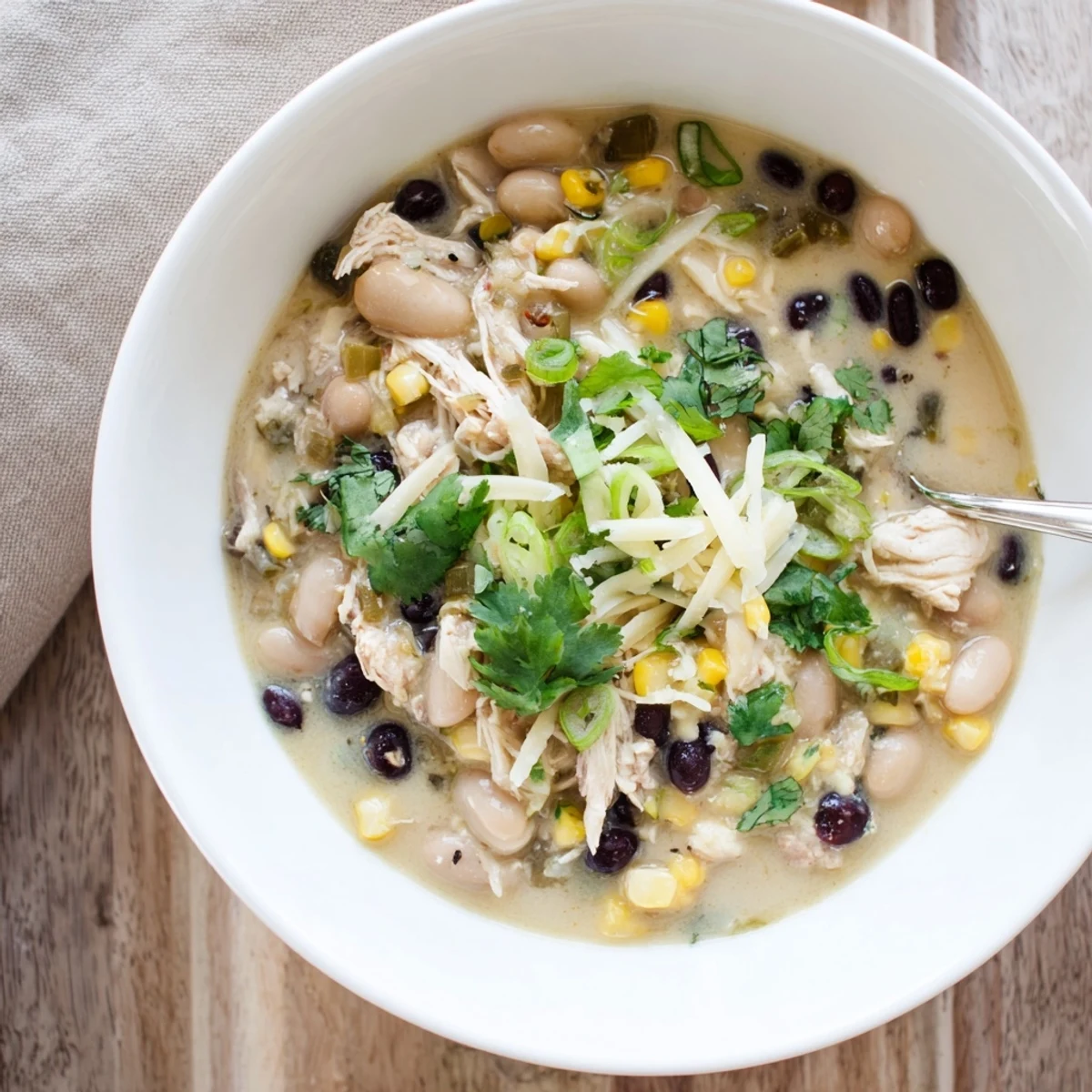 Hearty white chicken chili simmering with black beans, corn, and red bell pepper