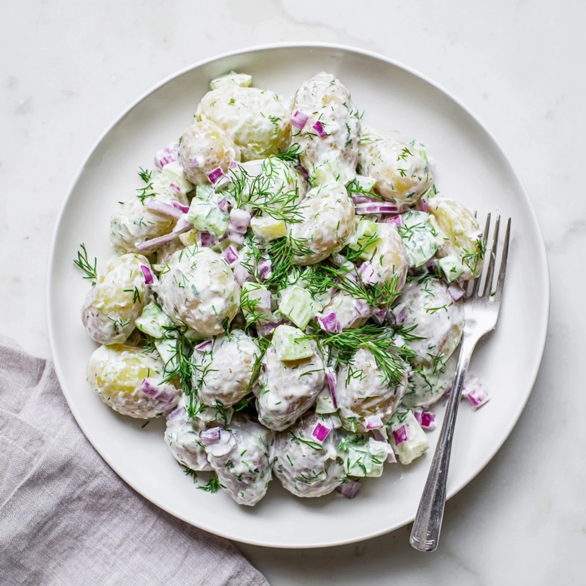 Creamy Greek yogurt potato salad with fresh dill, celery, and red onion in a white serving bowl