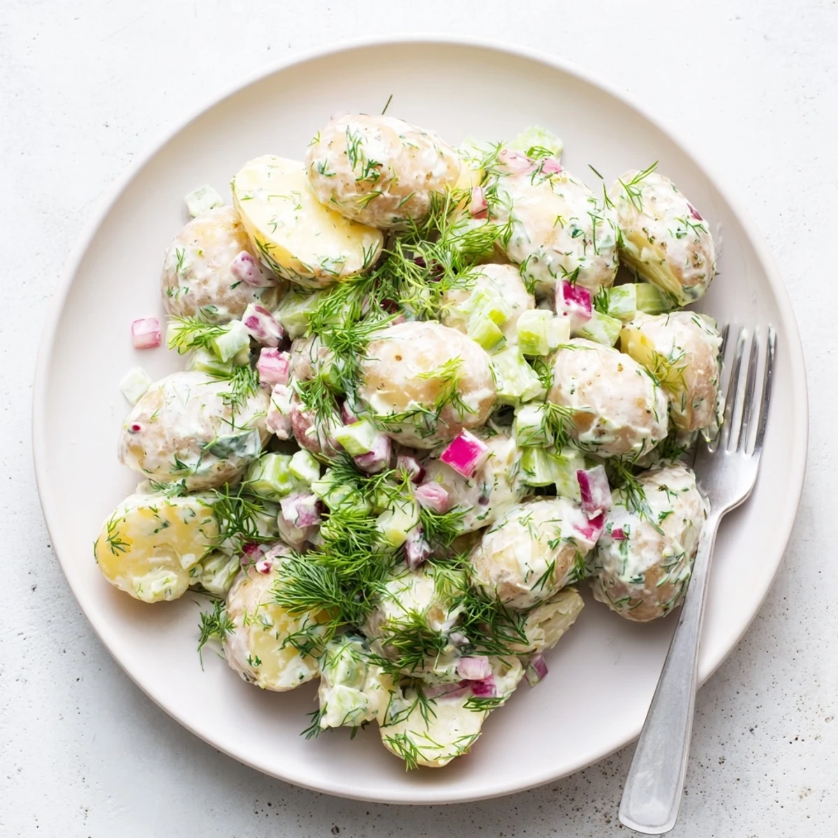 Lightened up potato salad featuring tender baby potatoes tossed in tangy Greek yogurt dressing with green herbs