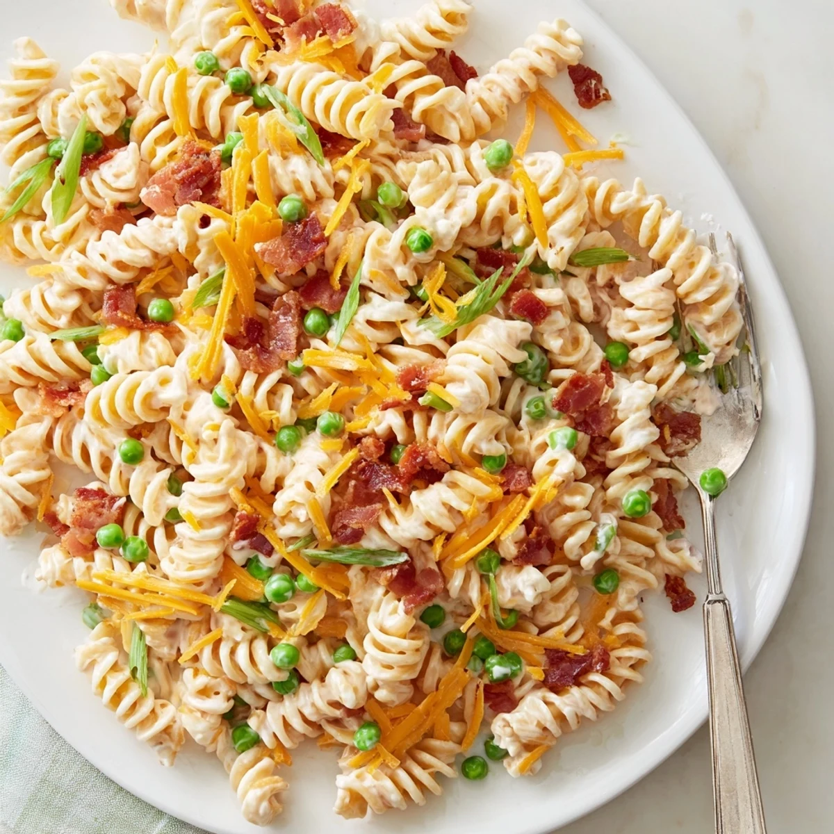 Heaping bowl of ranch pasta salad topped with crumbled bacon and green onions