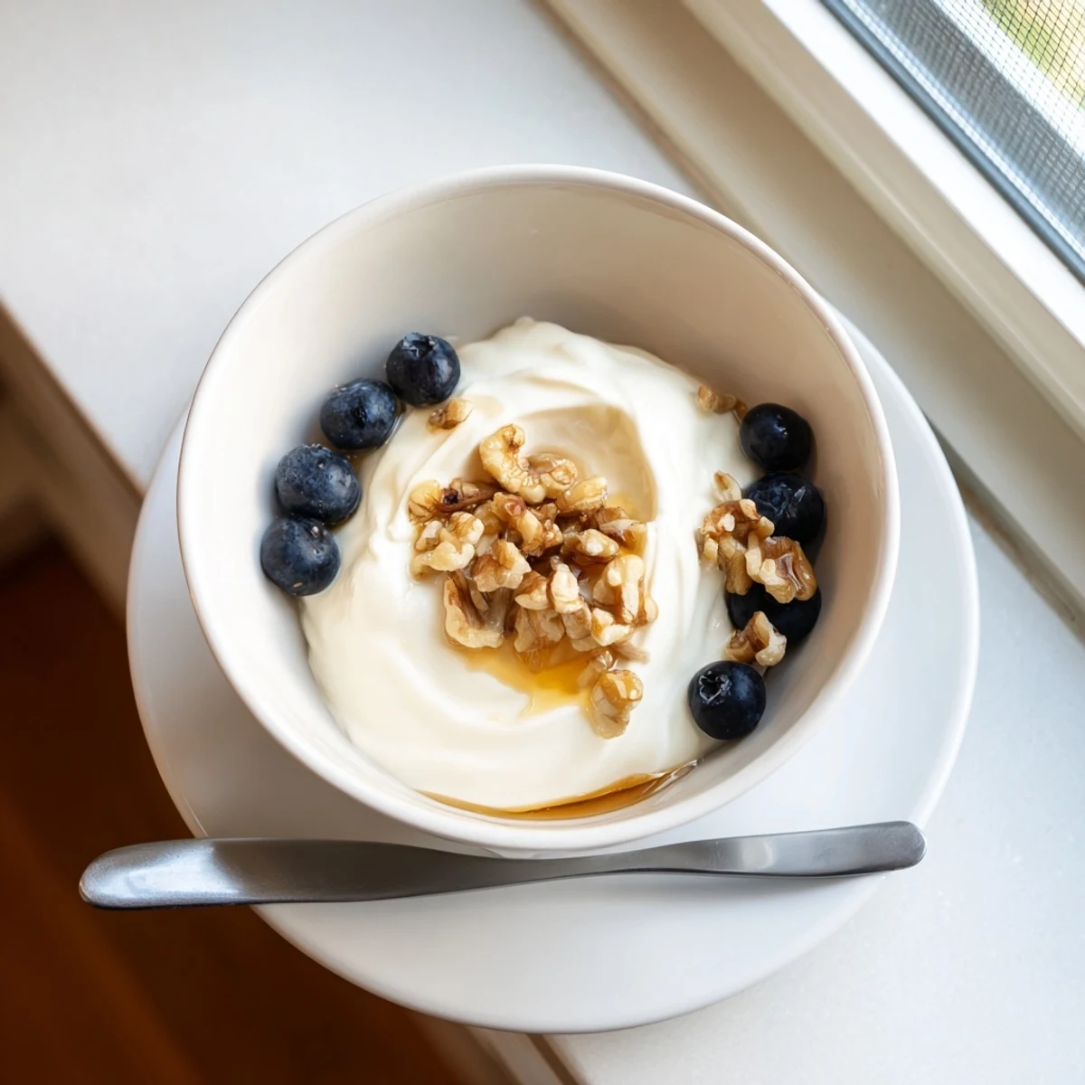 Creamy homemade Greek yogurt topped with fresh honey and walnuts in a white ceramic bowl