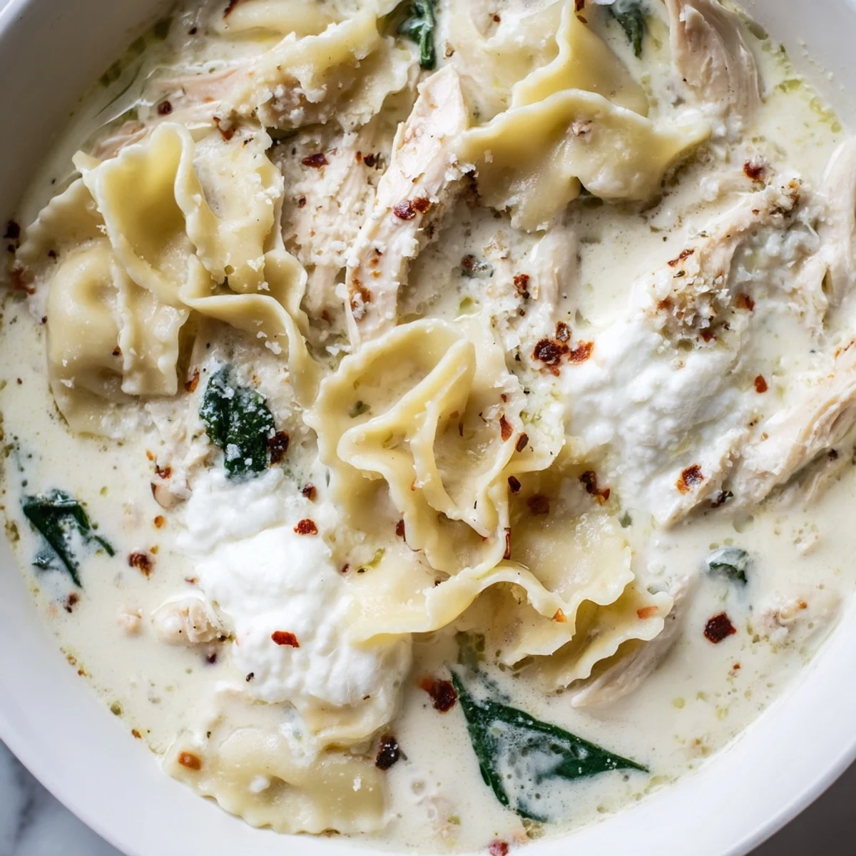 Creamy white lasagna soup with tender noodles and melted cheese in a white bowl