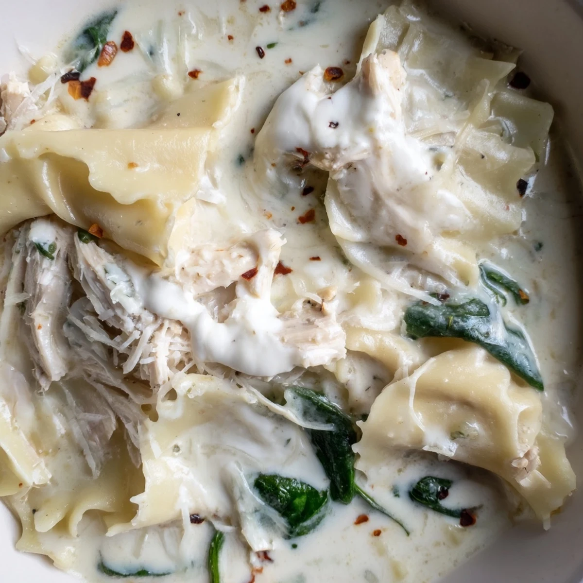 Rich and cheesy white lasagna soup ladled into a rustic bowl with crusty bread
