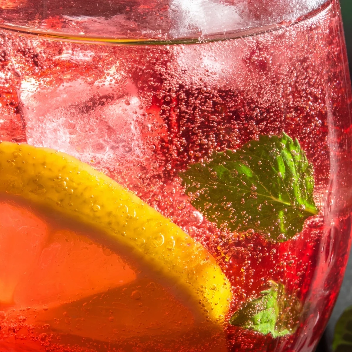 Vibrant cranberry honey lemon soda bubbling in a clear pitcher with sprigs of mint
