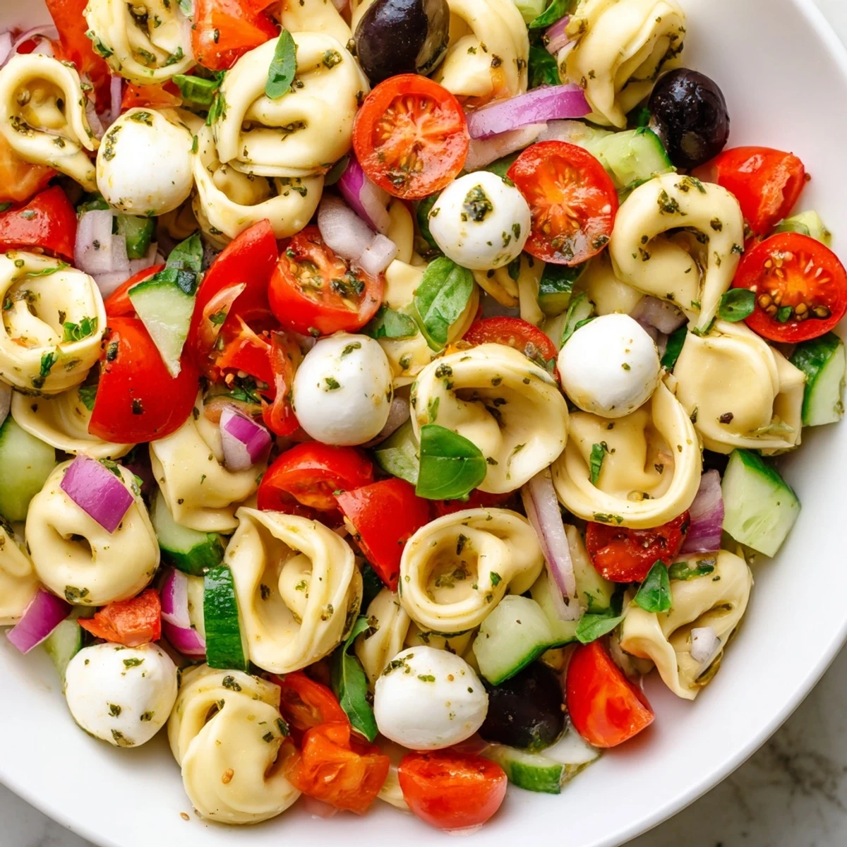 Colorful tortellini pasta salad with cherry tomatoes, cucumber, and mozzarella in a rustic serving bowl