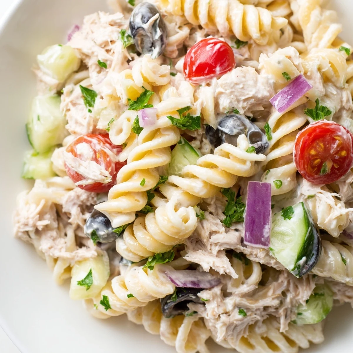 Tuna pasta salad garnished with fresh parsley and juicy cherry tomatoes