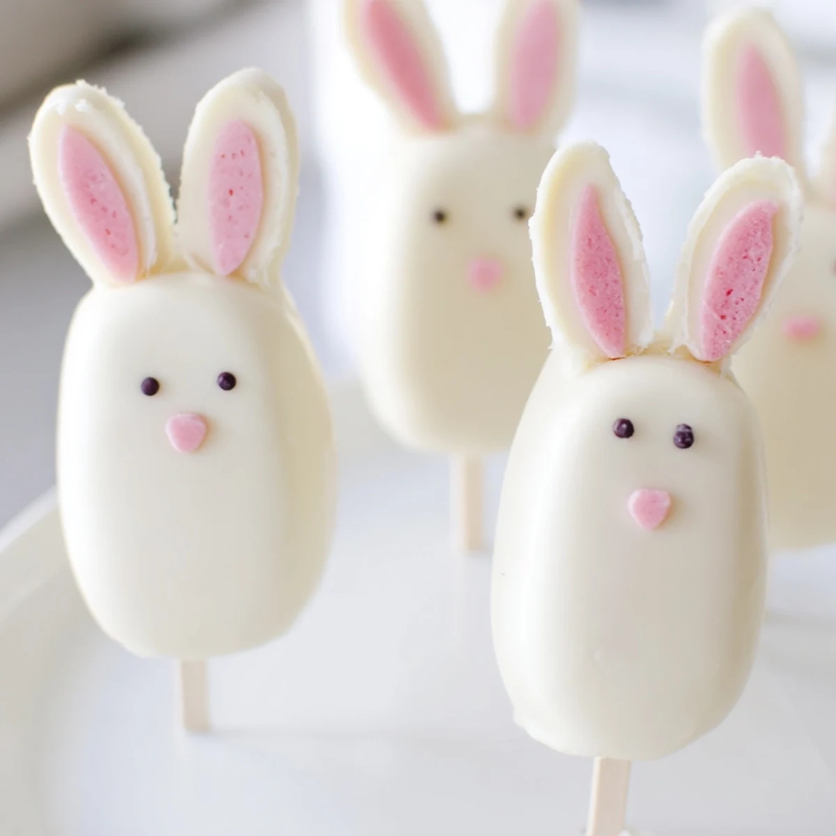 Creamy white chocolate bunny cakesicles decorated with sprinkles for festive Easter treats