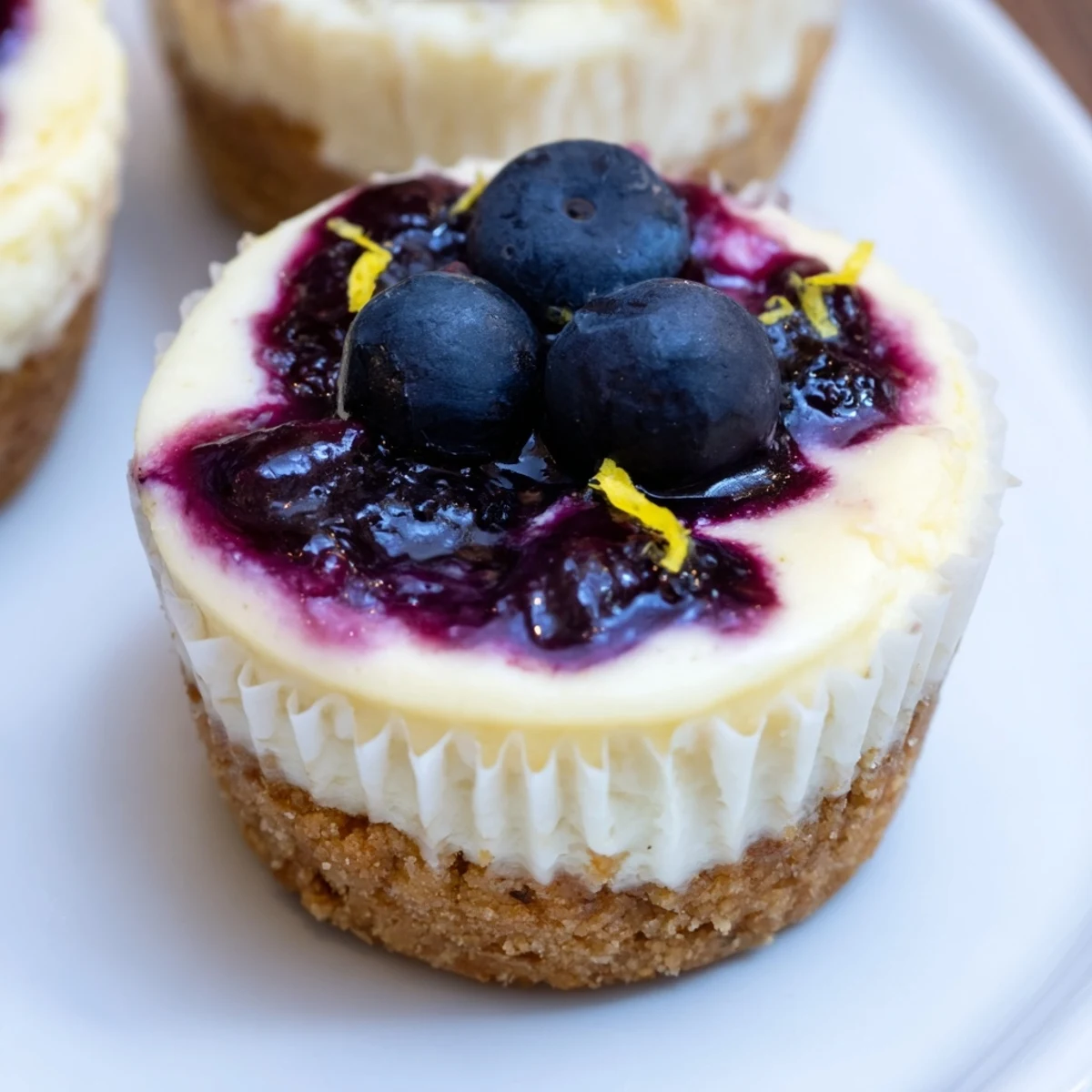 Creamy mini lemon blueberry cheesecakes topped with vibrant berry compote in muffin liners