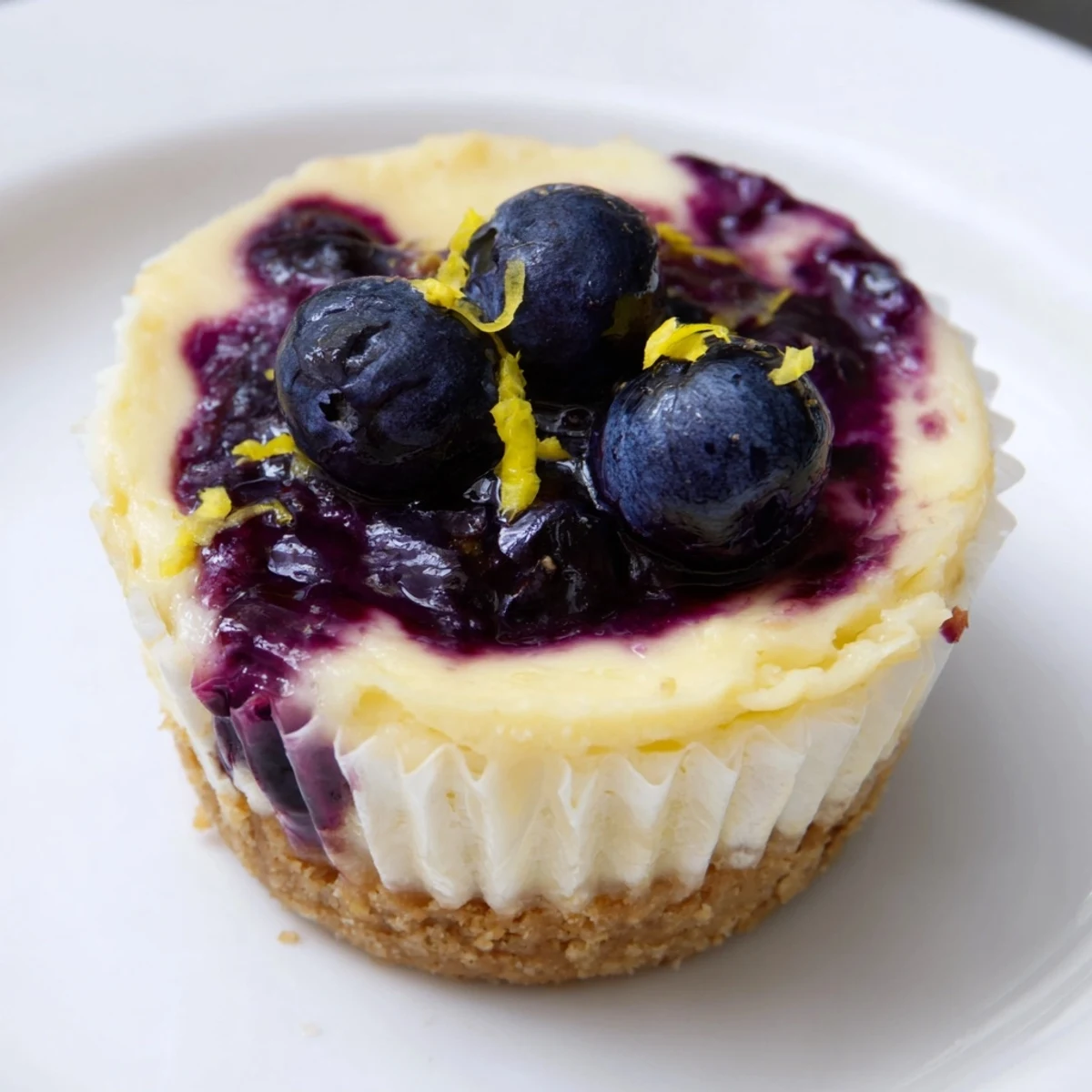 Golden graham cracker crusts cradle tangy mini lemon blueberry cheesecakes swirled with fruit