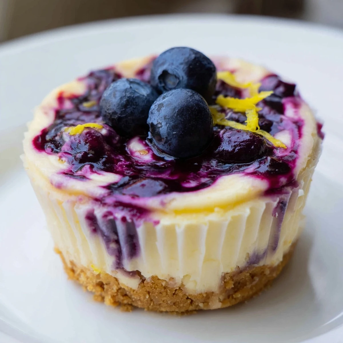 Chilled mini lemon blueberry cheesecakes garnished with fresh berries and bright lemon zest