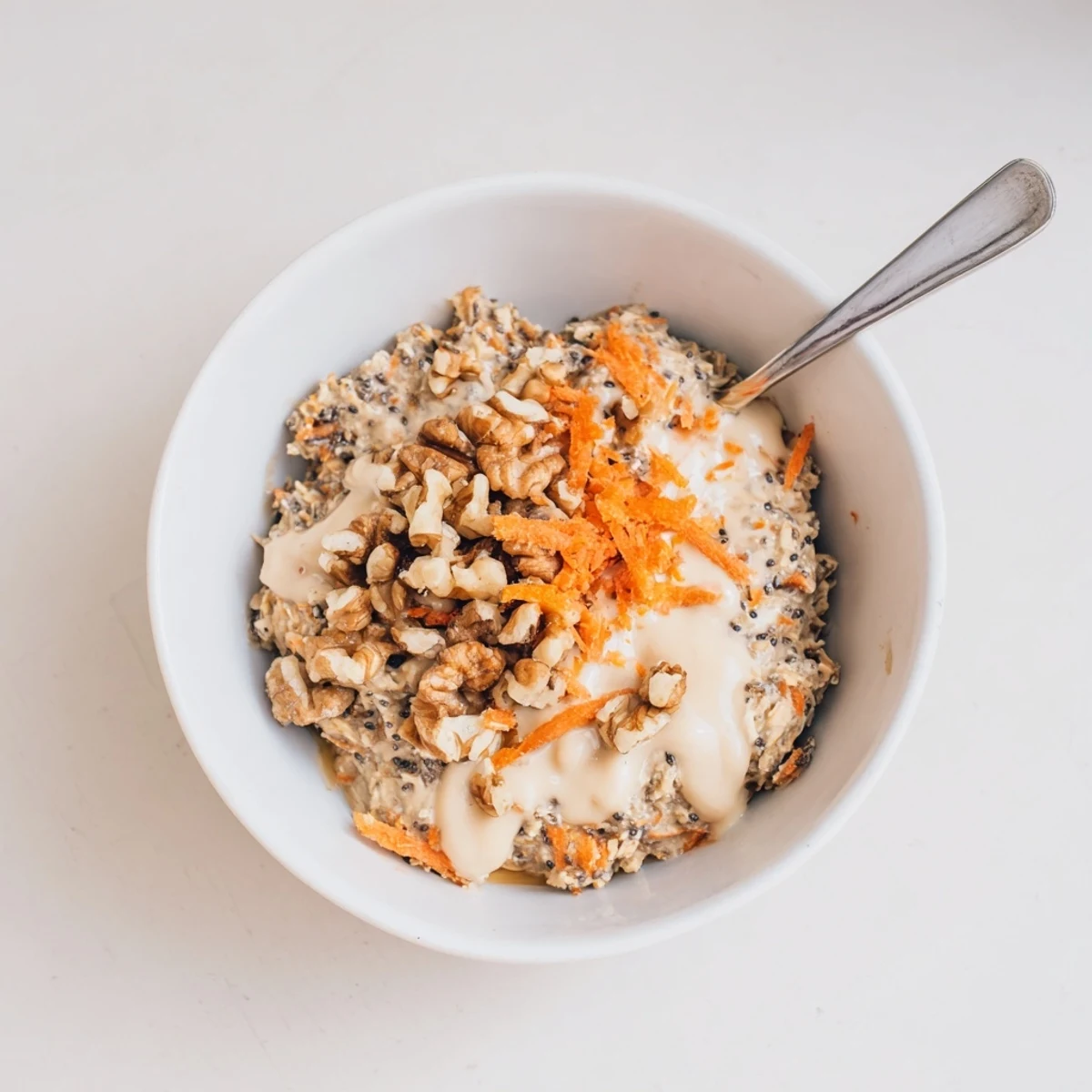 Creamy carrot cake overnight oats topped with cream cheese frosting and chopped walnuts in a mason jar