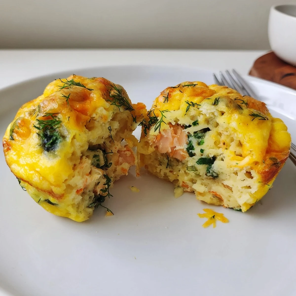 A plate of Smoked Salmon Egg Muffins garnished with lemon and herbs