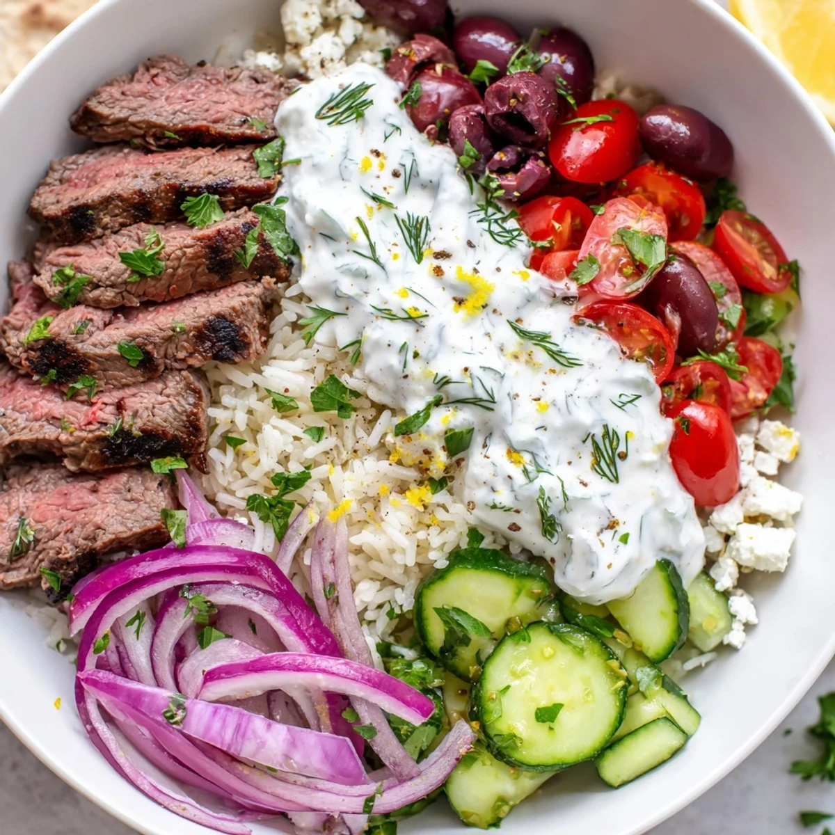 Juicy grilled Mediterranean steak bowl piled with fresh vegetables, herby rice, and creamy yogurt sauce