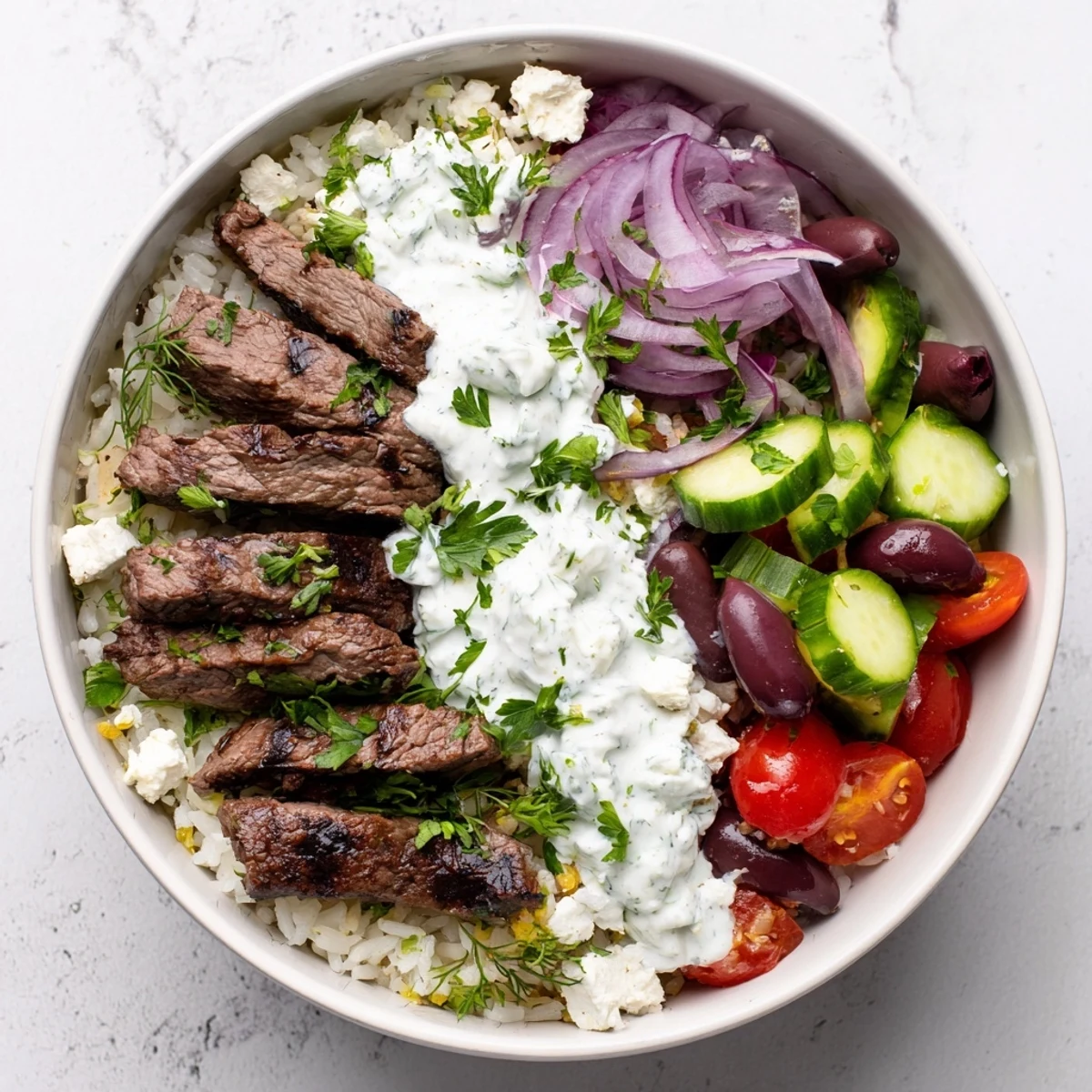 Colorful Mediterranean steak bowl featuring tender sliced steak, crisp veggies, feta, and zesty dressing