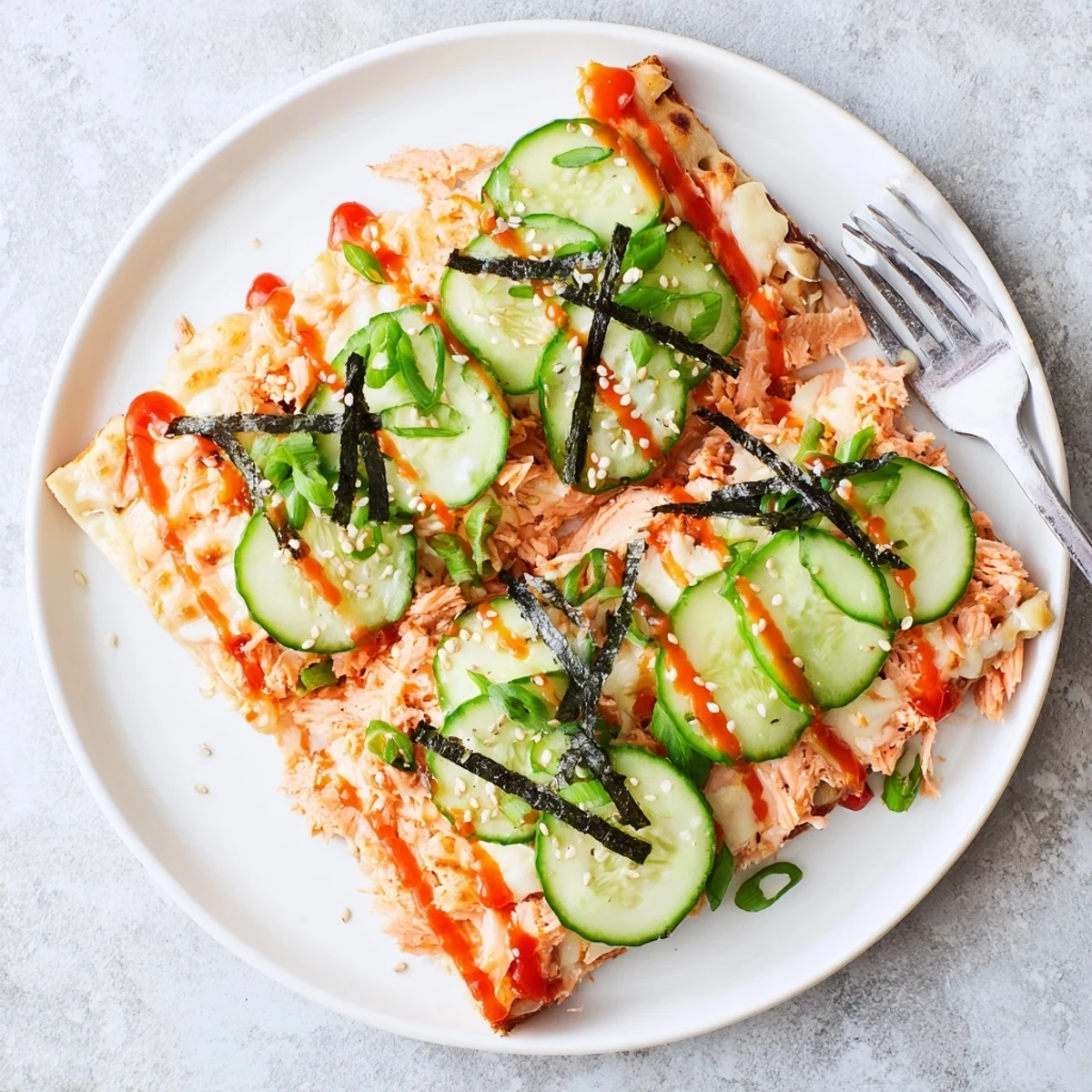 Golden baked salmon sushi flatbread pizza topped with fresh avocado slices and spicy mayo drizzle