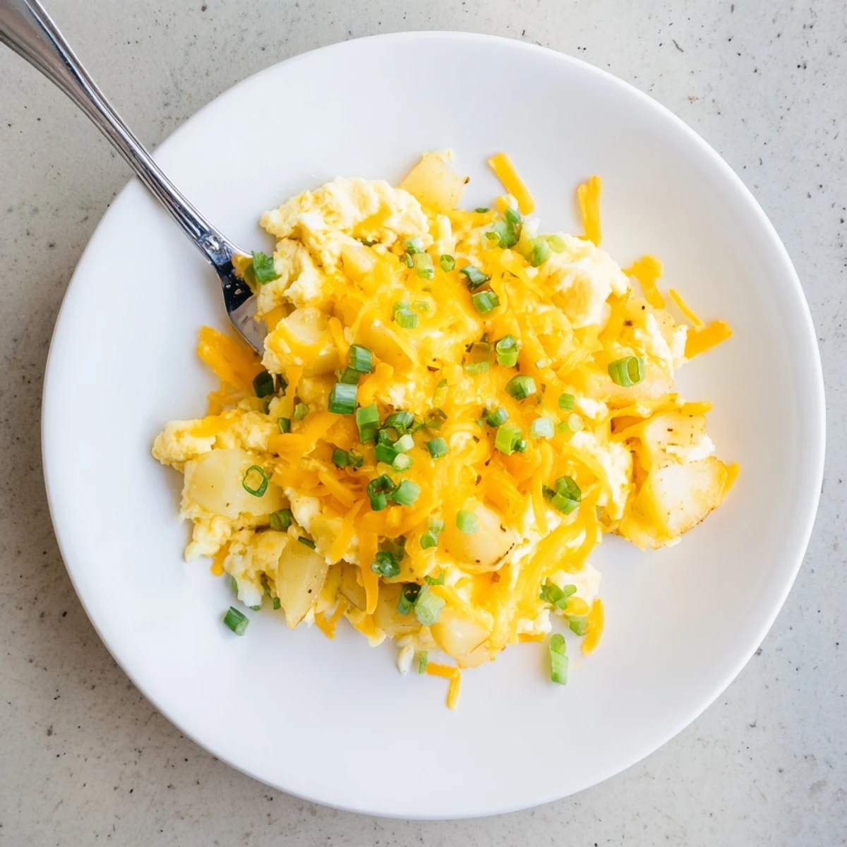 Hearty breakfast skillet of fluffy scrambled eggs with diced potatoes and gooey melted cheese